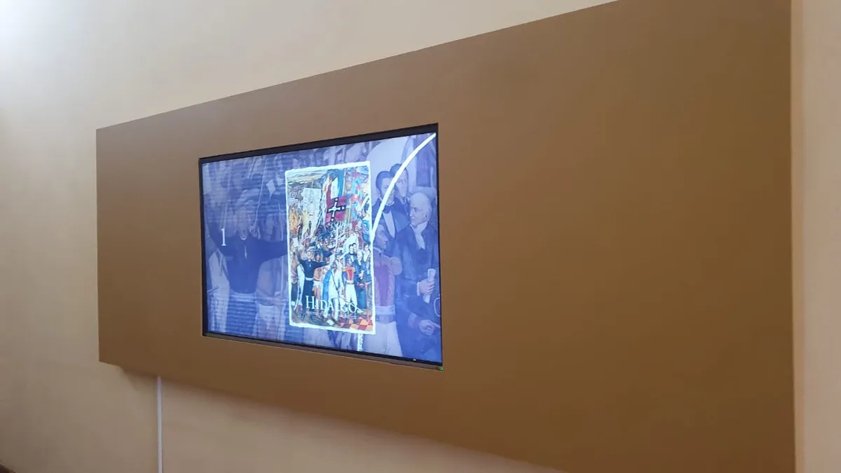 Sala expositiva con iluminación museográfica y obras sobre muro.