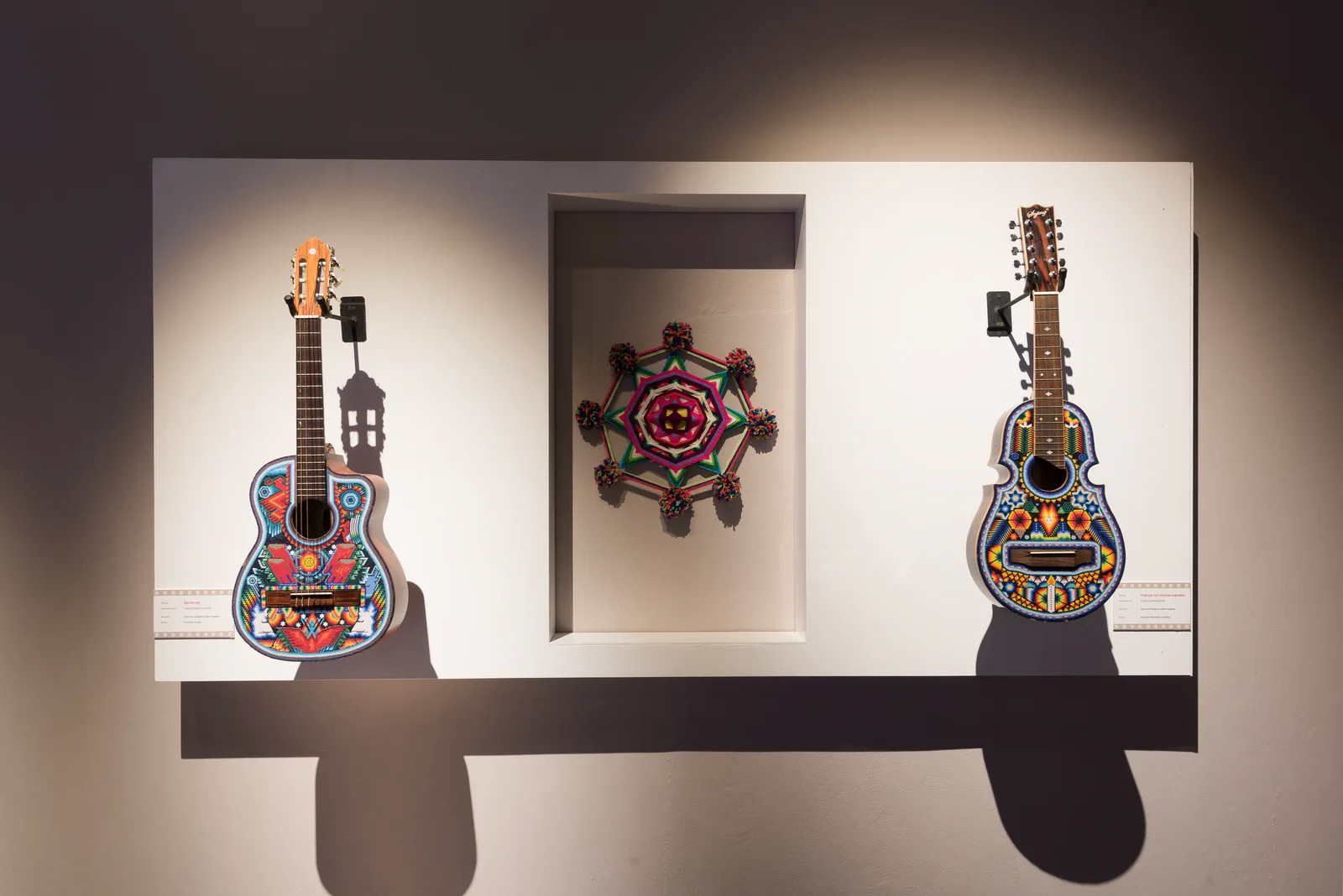 Guitarras Wixárika presentadas en un módulo expositivo.